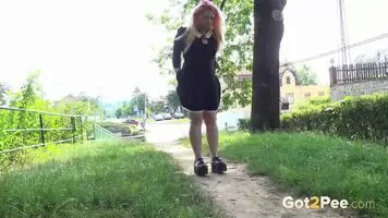 A blonde amateur girl lifts her dress to piss near to a quite busy road